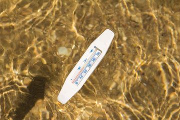 water thermometer in water measures the warm water of the red sea against the background of the sandy bottom view top