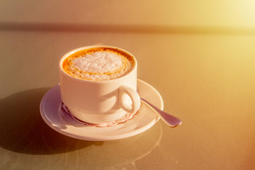 cup of cappuccino on a street table before sunset