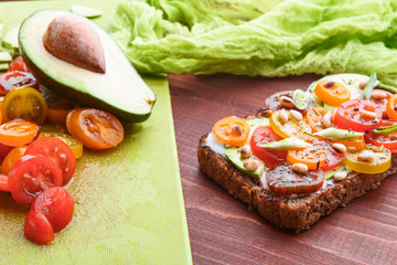 bruschetta with avocado, cherry tomatoes, blue cheese sauce, shallots. concept of a healthy breakfast with ingredients nearby