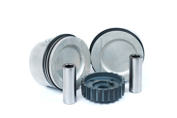 Close-up of spare parts two new pistons with connecting rods for a gasoline engine with installed sets of piston rings and crankshaft sprocket on an isolated white background