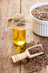 Flax seeds and oil in bottle on wooden background