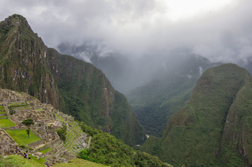Obraz premium View of the Lost Incan City of Machu Picchu and Huayna Picchu mountain from Machu Picchu mountain .Low clouds .Cusco Region,Sacred Valley, Peru