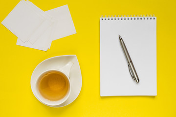 Notepad, pen, tea on a yellow background flat top view with copy space,layout,mocap