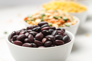 Different beans in bowls on a white wooden table