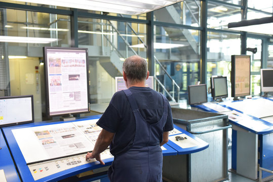 Arbeiter in der Druckvorbereitung einer Druckerei f&uuml;r Zeitungen - Layout Kontrolle vor dem Druck // Pre-press worker in a newspaper printing plant - Layout control before printing