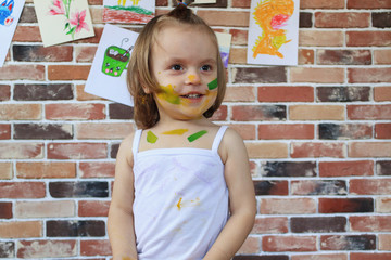 Beautiful little smiling baby girl with face painted in colorful paints