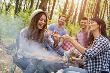 Group of friends making barbecue and having fun outdoor