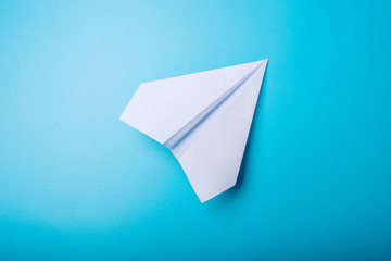 White paper origami airplane lies on pastel blue background