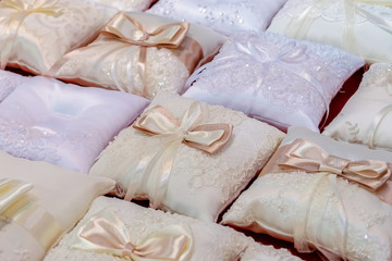Many small pillows for the wedding rings on red background. Closeup view.