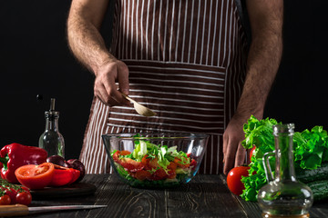 Man preparing salad with fresh vegetables on a wooden table. Cooking tasty and healthy food