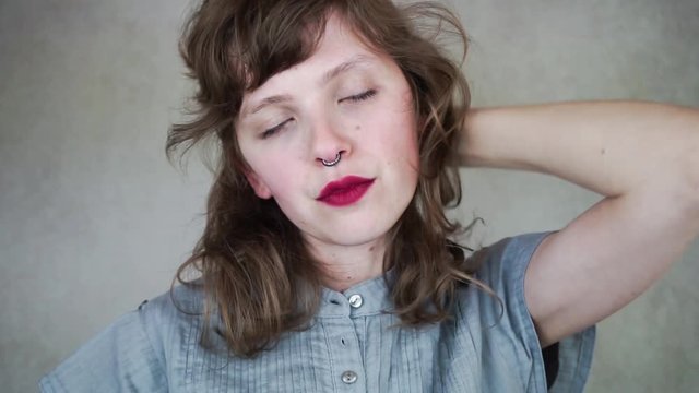 Mujer joven relaj&aacute;ndose mientras se toca el pelo 