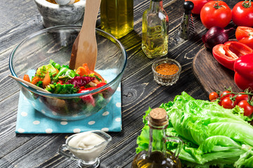Man preparing salad with fresh vegetables on a wooden table. Cooking tasty and healthy food. Close-up