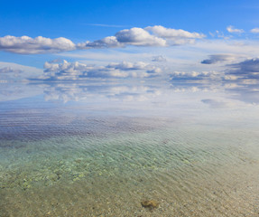 Sandy calm sea, blue sky with few clouds background, crystal aquamarine transparent sea.