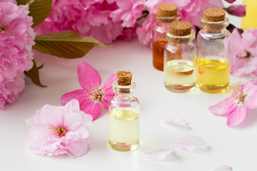Fototapeta na wymiar Bottles of essential oil with pink cherry blossoms