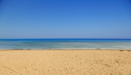 Sandy beach, calm sea, clear blue sky background. Summer destination.
