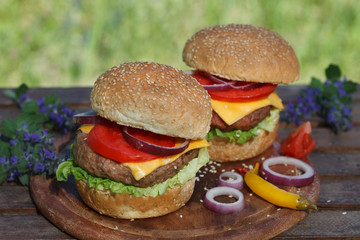 Two classic cheeseburgers on wooden board.  Soul food.