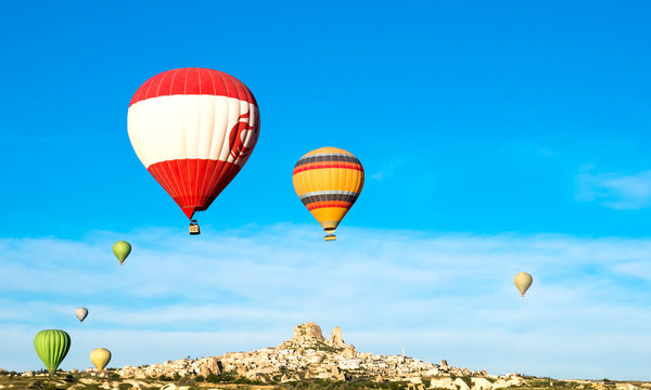 Colorful hot air balloons flying near Uchisar castle at sunrise, CappadociaTurkey
