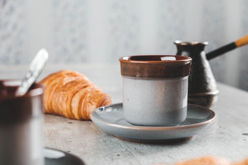 Coffee in cups, croissant and cezve on the table.