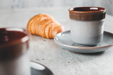 Table served for breakfast with two coffe cups and croissant