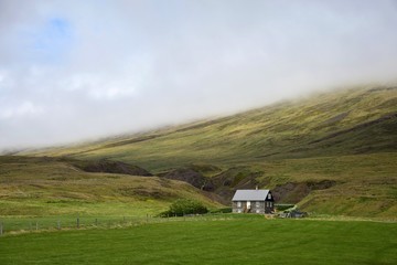 Icelandic scenery - a small house in front of mountains on the peninsula Vatnsnes