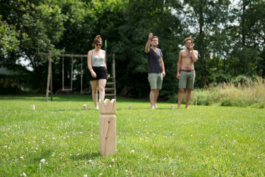 Family playing Kubb game during summertime in the garden