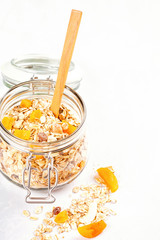 Jar with homemade granola or oatmeal muesli with nuts and dried fruits. Healty diet breakfast, vegan or vegeterian food concept