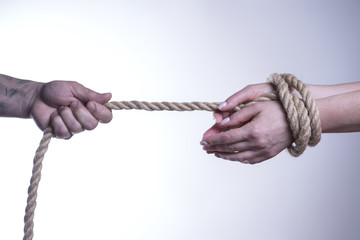 Men's hands pull a rope with tied women's hands on a white background.