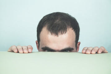 Caucasian businessman peeking over desk.