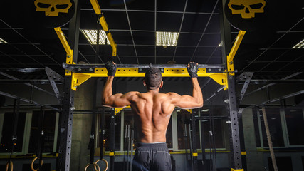 athletic african american man does pull-ups in gym on beam. power pull Up workout. how looks muscles during pulling