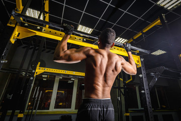 athletic african american man does pull-ups in gym on beam. power pull Up workout. how looks muscles during pulling