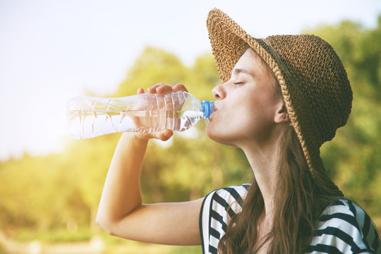 Woman drinking water in summer sunlight