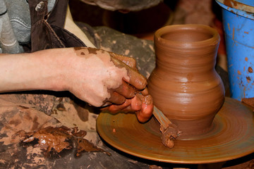 Creating a jar or vase of clay close-up. Master crock. Man hands making clay jug macro.The sculptor in the workshop makes a jug out of earthenware closeup. Twisted potter's wheel. Сeramics art concept