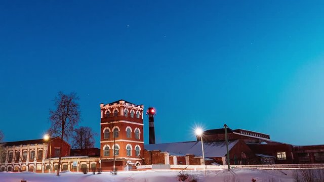 Dobrush, Gomel Region, Belarus. Time Lapse Time-lapse Timelapse From Evening To Night Of Old Paper Factory Tower In Winter Season. Night Stars Sky Above Historical Local Landmark