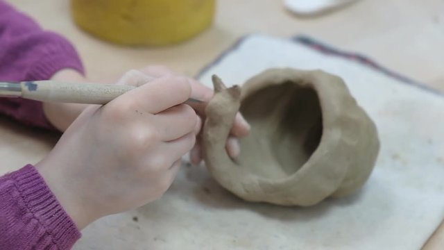 The child learns to mold different kinds of clay products in a ceramic workshop. The child works independently with clay in a lesson in a creative lesson.