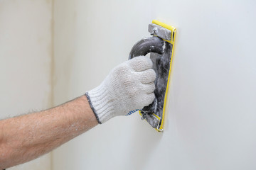 Hand smoothing out wall with sandpaper