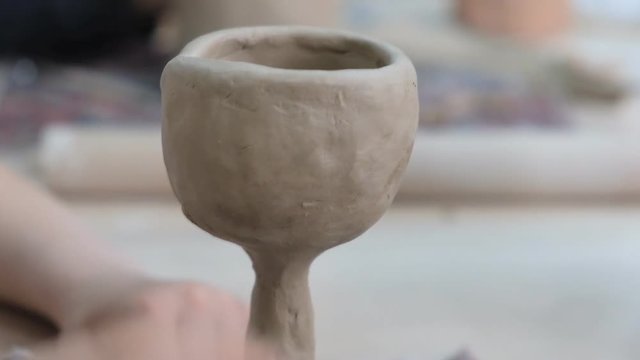 The child learns to mold different kinds of clay products in a ceramic workshop. The child works independently with clay in a lesson in a creative lesson.