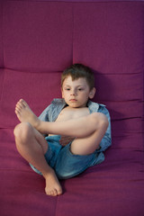Naklejka premium slacker cute little kid lying on couch resting watching TV