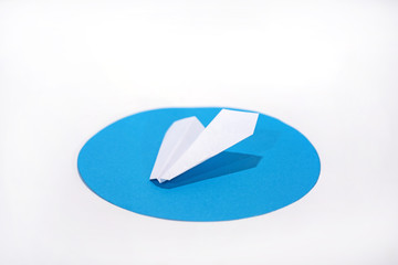 White paper plane on round blue circle.