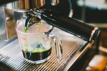 Barista making hot green tea using coffee maker machine, close-up on the measure scale glass. Cafe lifestyle, Food and drink small business, or beverage concept