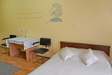 Fragment of an interior of the double hotel room with a portrait of the Russian poet A.S. Pushkin and the quote on a wall