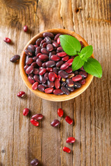 Red raw beans with greens on a wooden table.