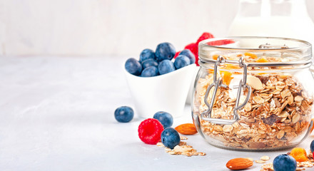 Jar with homemade granola or oatmeal muesli with nuts, dried fruits and fresh berries. Healty diet breakfast, vegan or vegeterian food concept