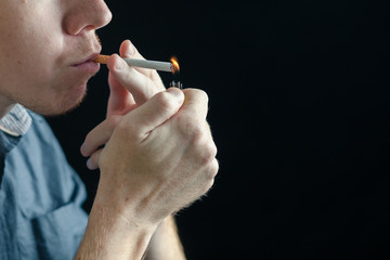 Fototapeta premium Man fire a cigarette. Black background.