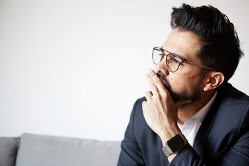 Portrait of dreaming handsome bearded man taking rest at home. Young handsome man wearing glasses thinking with close eyes against empty white wall in the background
