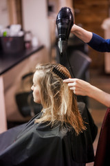 hairdresser stylist dries wet hair with hair dryer