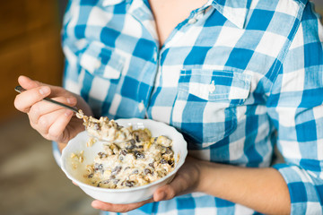 The girl in jeans and a plaid shirt holding a plate of muesli mixed with a yogurt. Healthy eating concept. Proper nutrition. Healthy food.