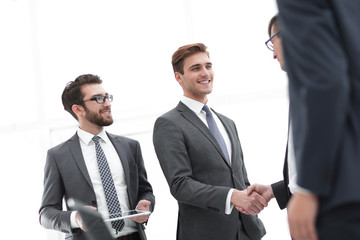 Fototapeta premium Two cheerful businessmen shaking hands with smile at office with