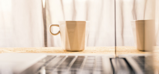 Coffee cup and laptop on coffee desk