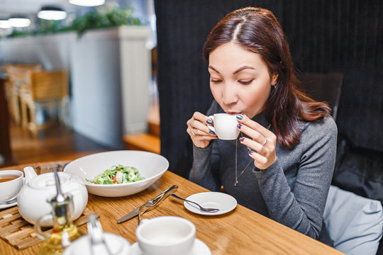 Young eastern woman drinking strong aroma coffee in a cafe