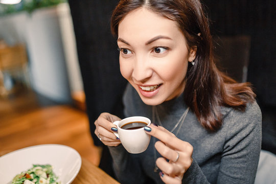 Young eastern woman drinking strong aroma coffee in a cafe